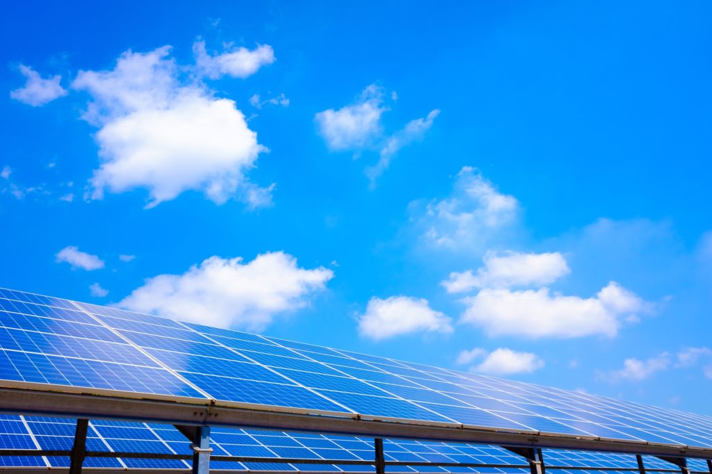 Installation of solar panels in a mountain area with blue clouds.